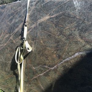 Large slab of dark green and brown stone with white streaks, secured with a beige strap.