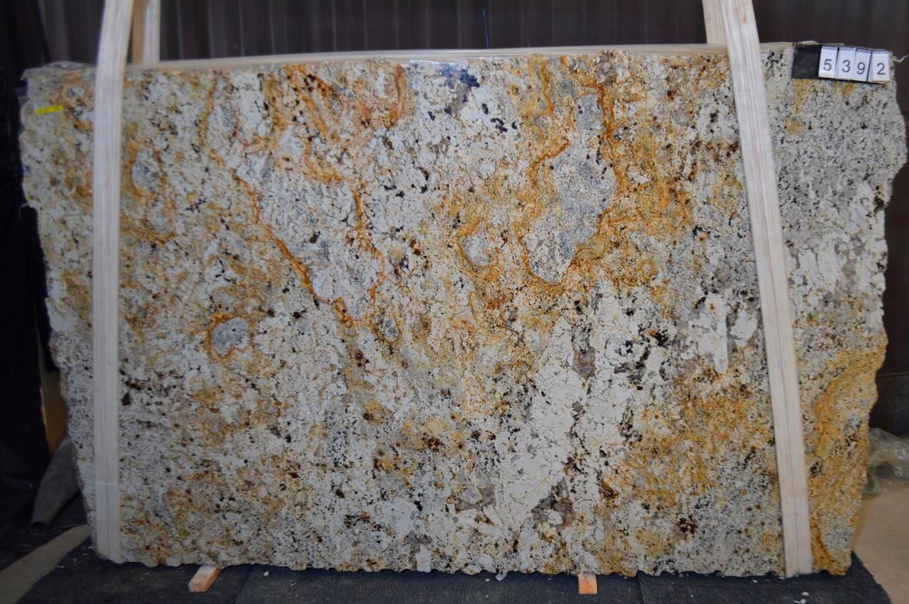 Large slab of golden granite with dark and light patches, supported by wooden bracing.