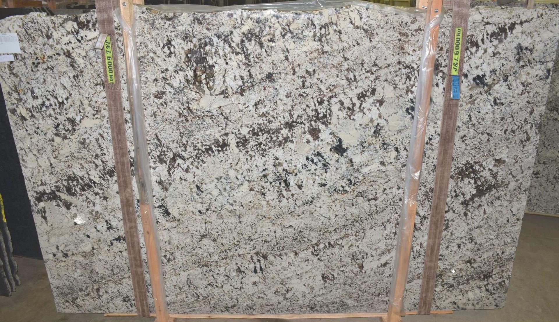 Large granite slab with white, brown, and gray mottled patterns, supported by wooden braces.