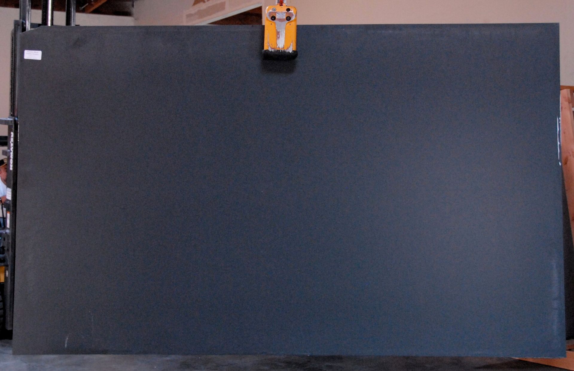 Large, dark slab of stone, held by a crane.