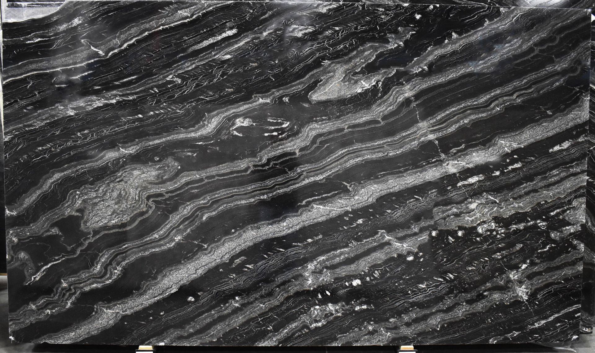 Black and gray granite slab with wavy white and silver veining.