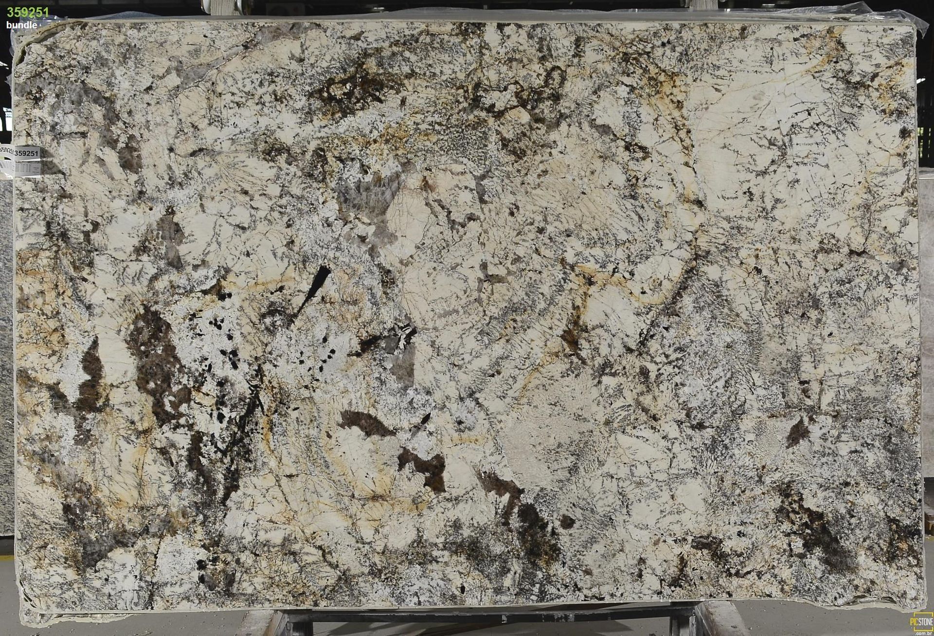 Cream and brown granite slab with dark veining and golden speckles, ready for countertop use.