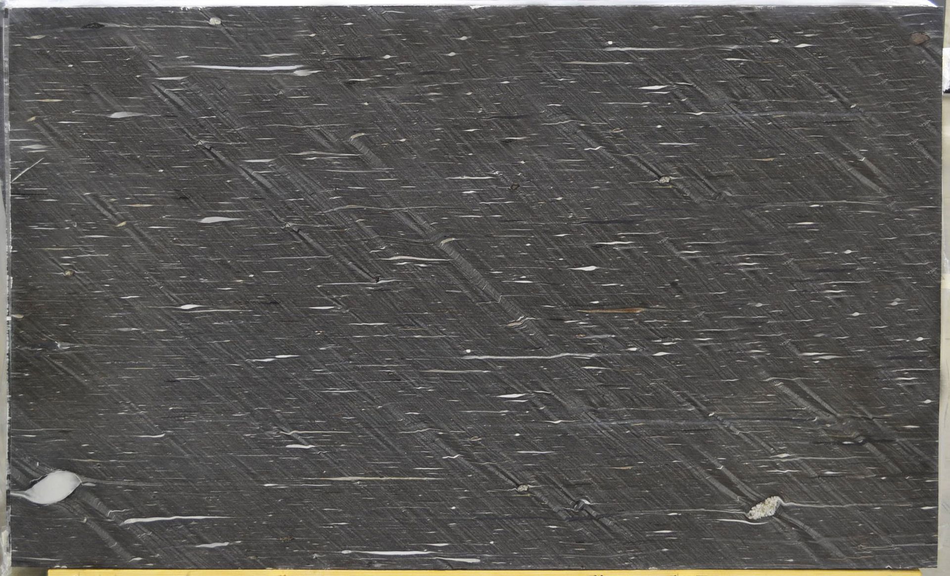 Black marble tile with diagonal scratch marks and white flecks.