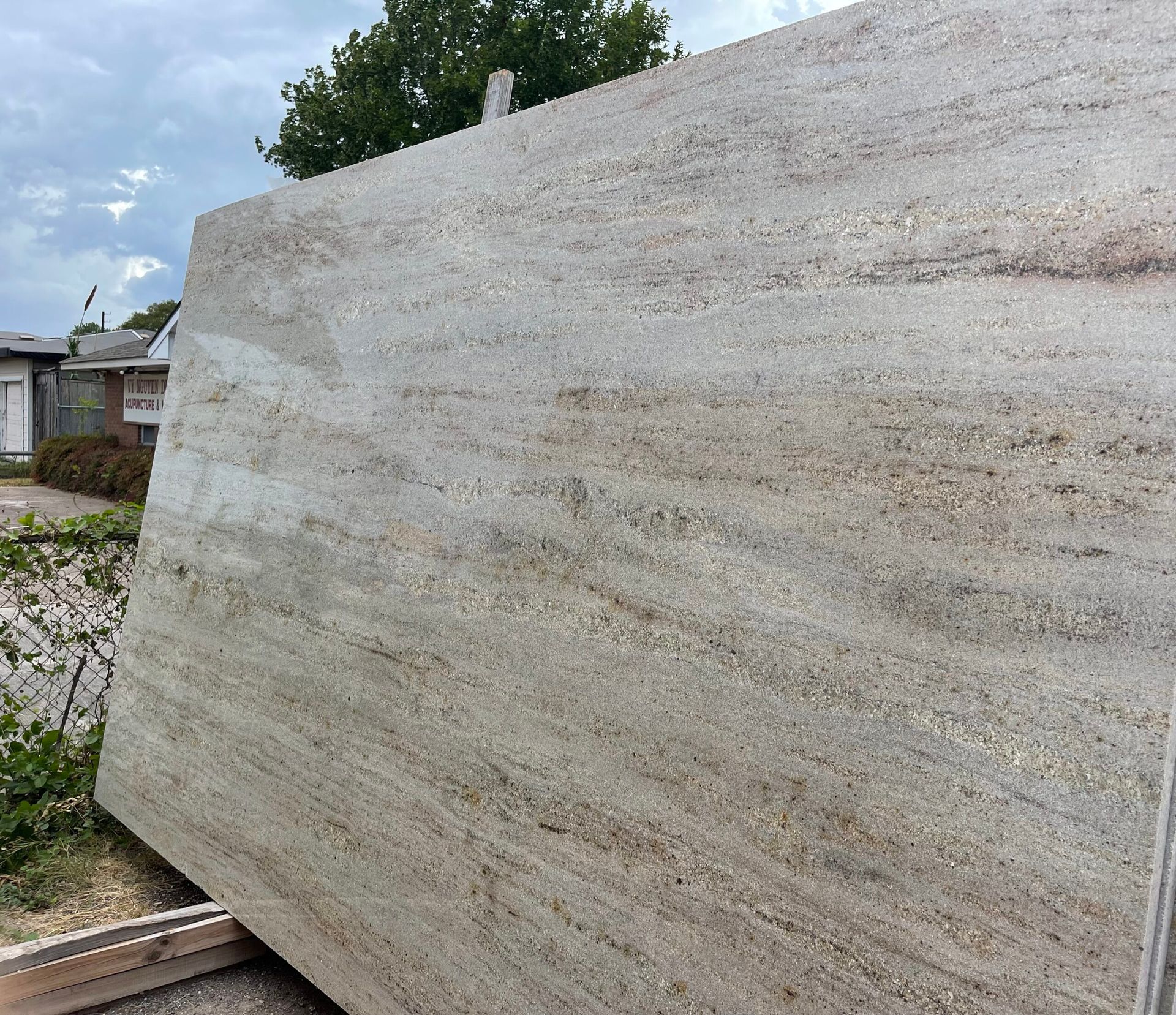 Large slab of granite with beige and brown veining, outdoors.