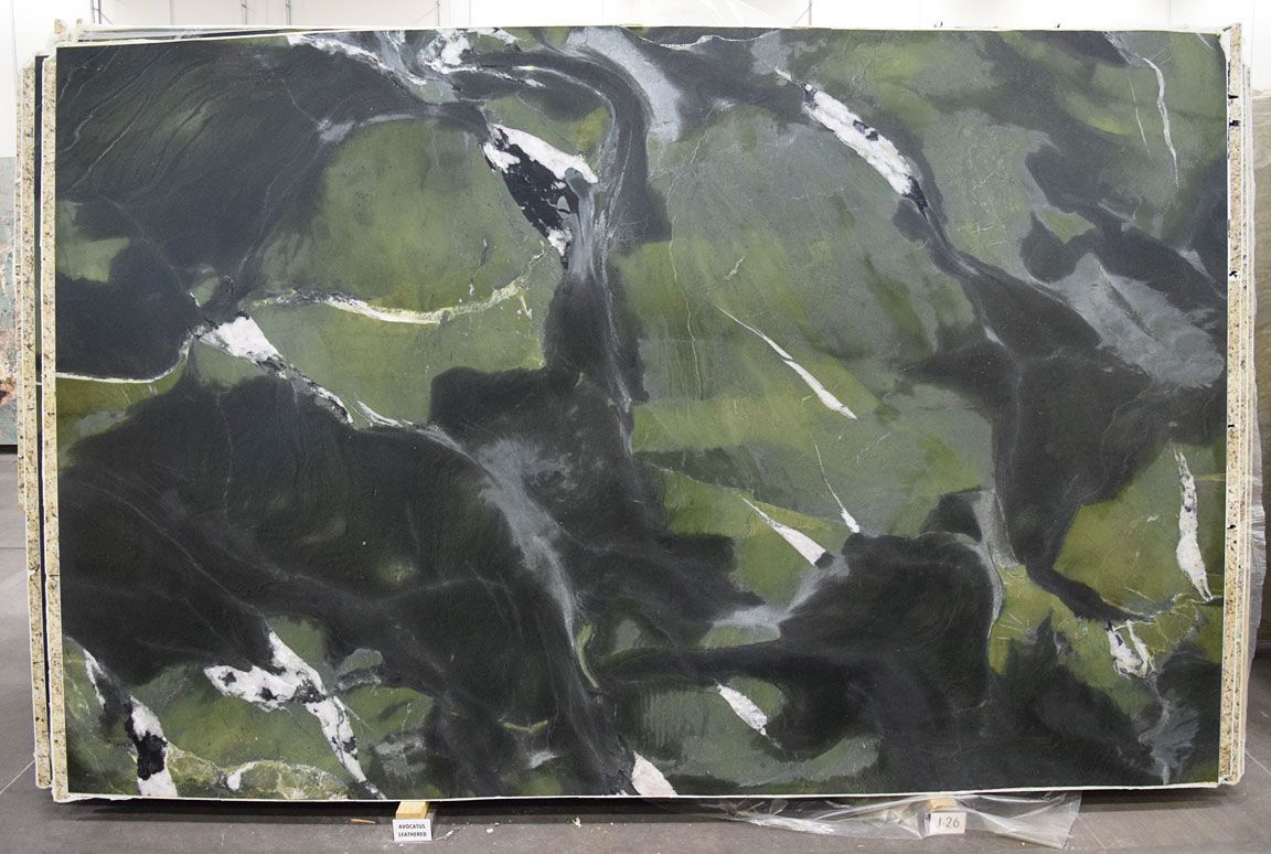 Green, black, and white marble slab with flowing patterns, likely for countertops or flooring.