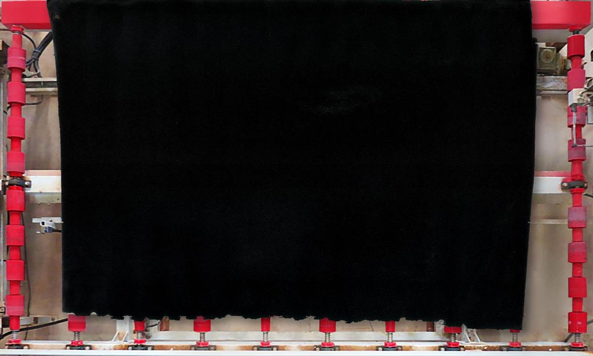 Black fabric stretched on a red and white frame, likely for processing or display.