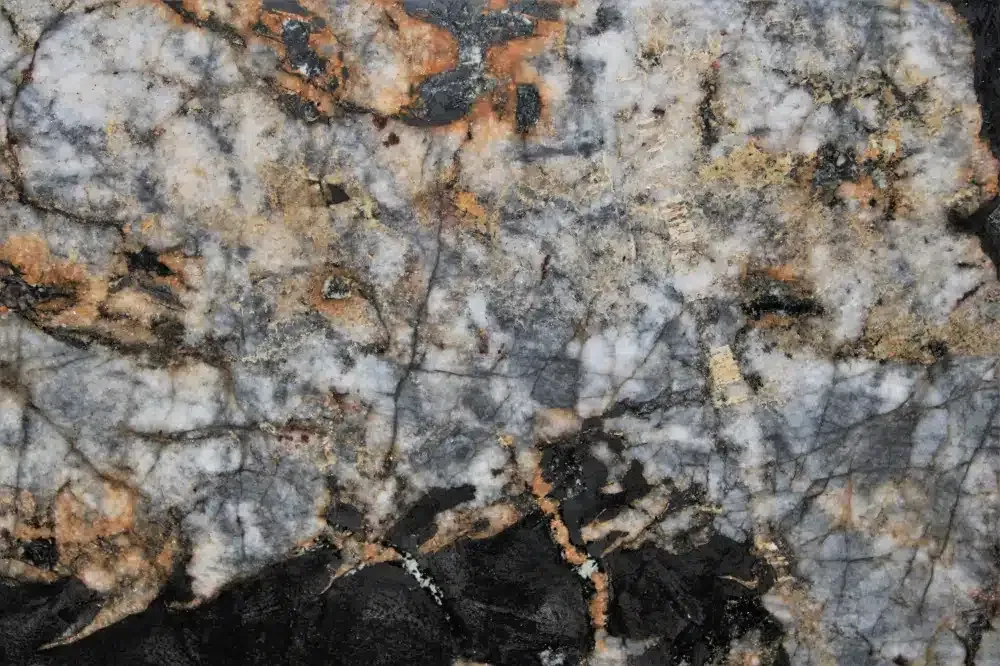 Close-up of a granite rock with white, black, gray, and orange veins.