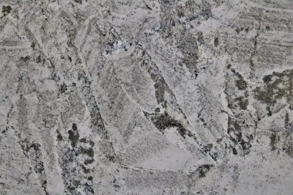 White granite countertop with gray and black veining and spotting.