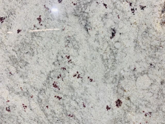 Granite countertop with white and gray swirls, dark red flecks.
