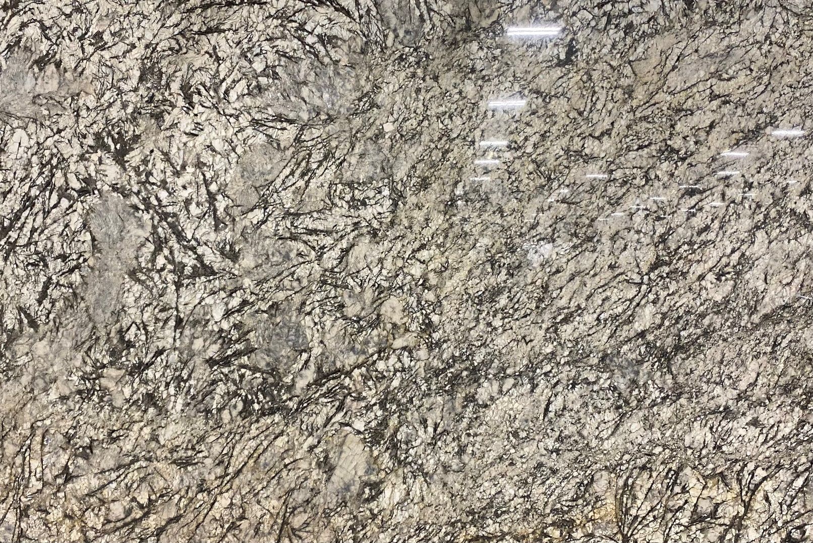 Tan granite slab with a rough, textured surface and dark veining.
