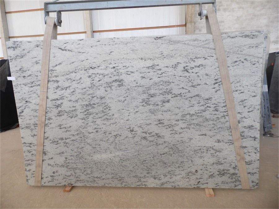 Large white granite slab with gray veining, supported on wooden beams.