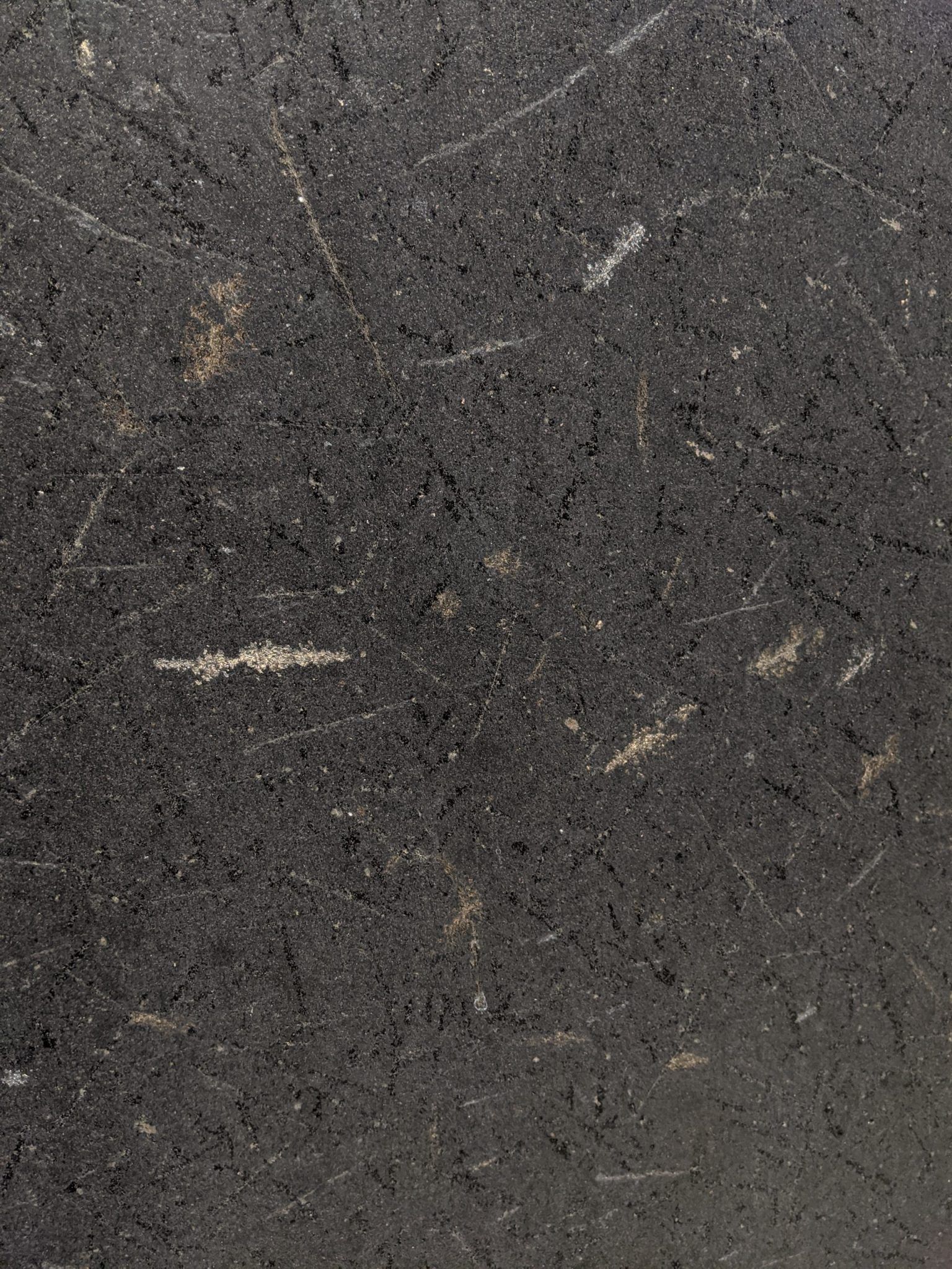 Close-up of dark gray asphalt surface with faint white scratches.