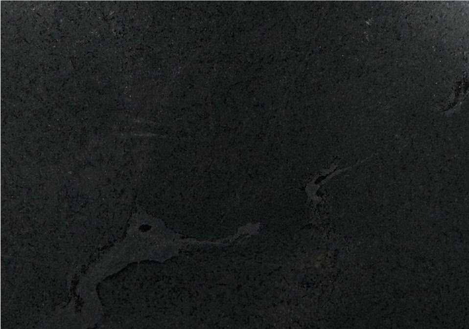 Dark, textured surface with lighter, irregular shapes and streaks.