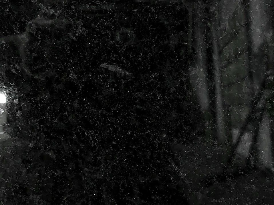 A dark, wet surface with blurred shapes and light reflections.