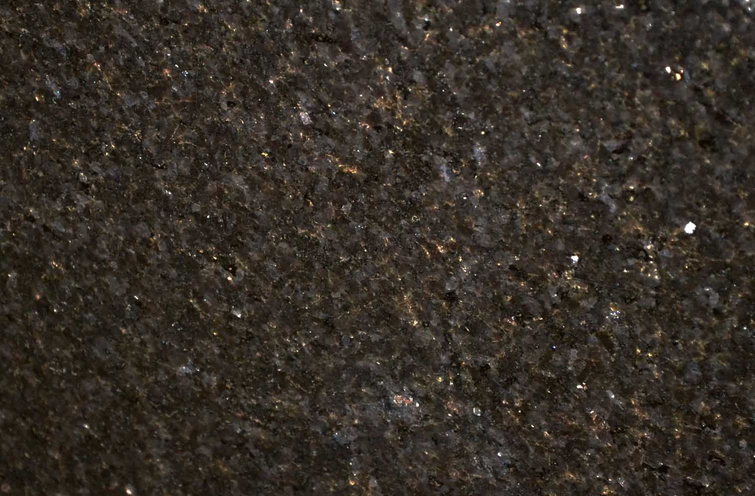 Dark, textured stone surface with flecks of light.