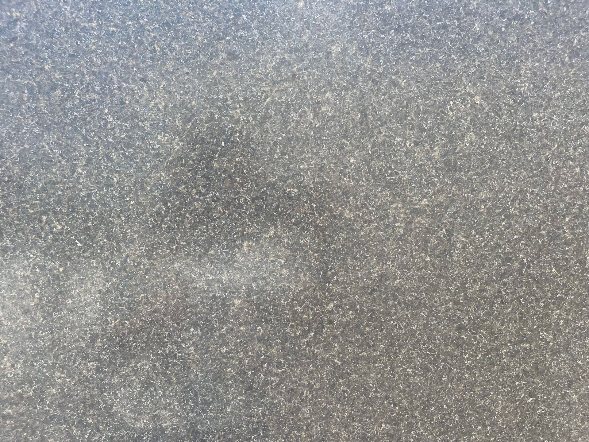 Granular gray textured surface, possibly asphalt or concrete.