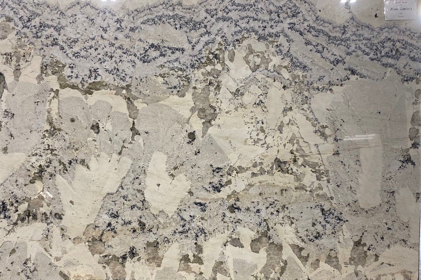 White and beige granite slab with dark gray and black speckles, suitable for countertops.