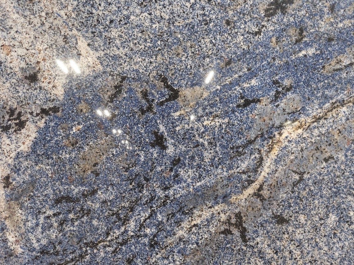 Close-up of granite with blue, white, and black specks and swirling patterns.