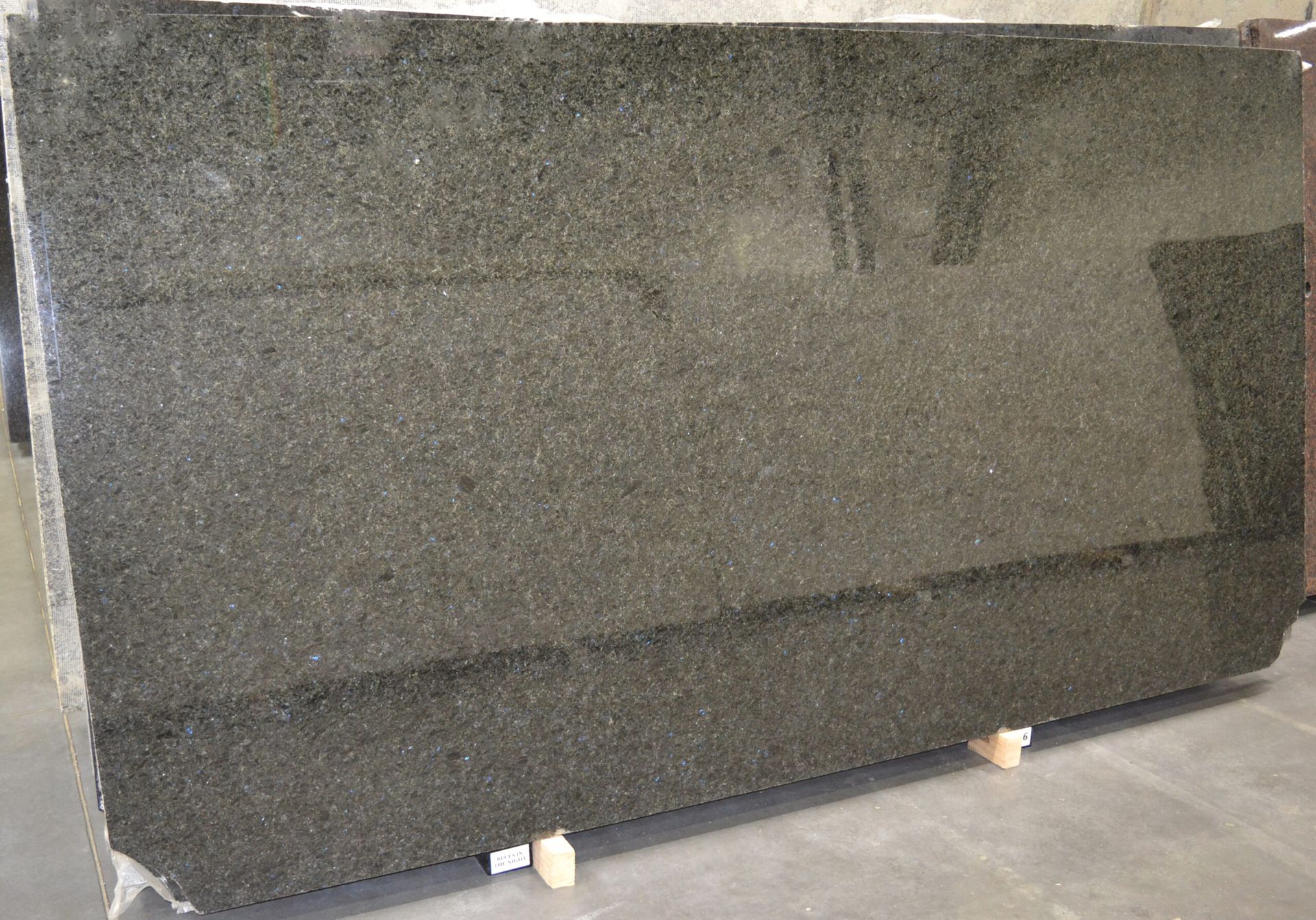 A large slab of dark gray granite, likely for countertops, resting on wooden supports.