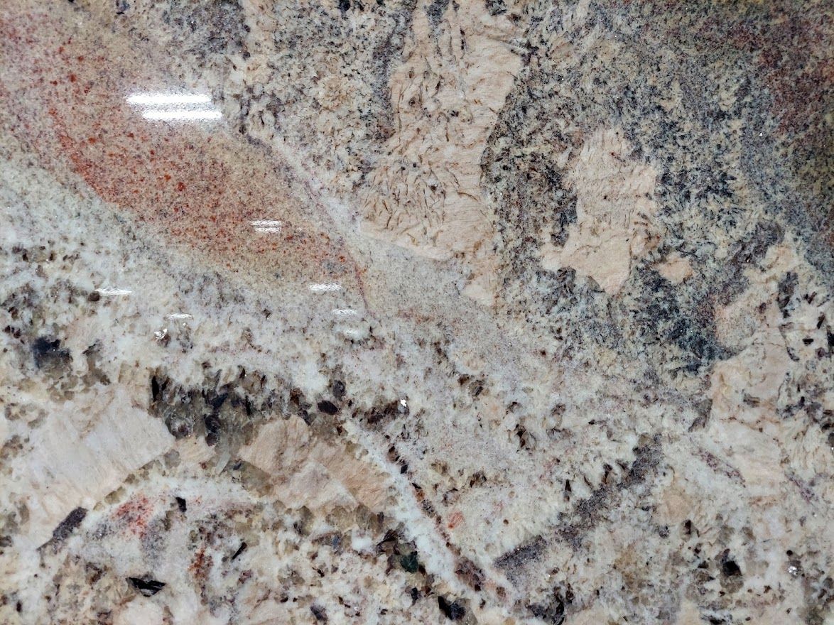 Granite countertop with beige, brown, and black mottled patterns and some pinkish-red streaks.