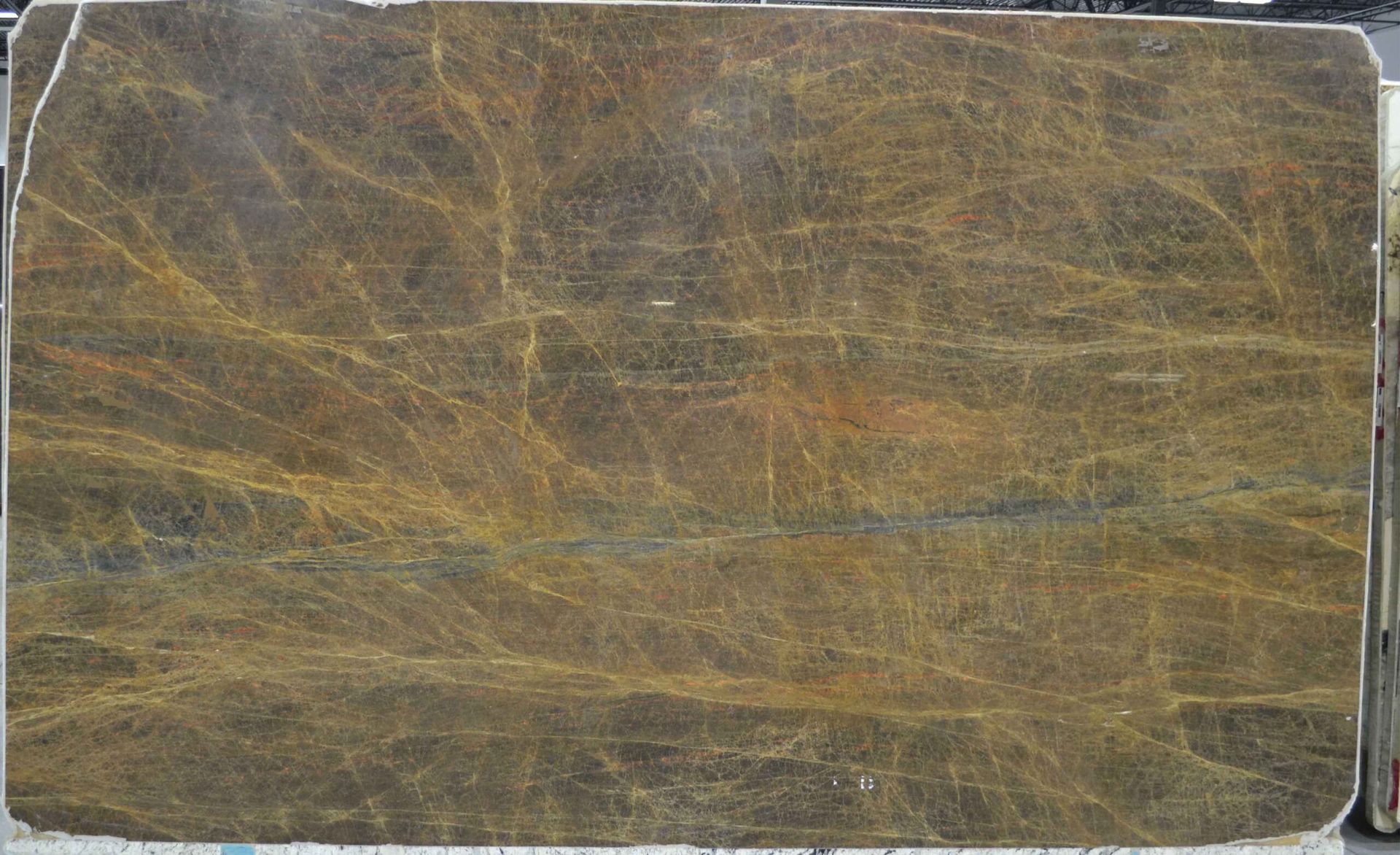 Large, rectangular slab of brown, gold, and black marble with linear and veining patterns.