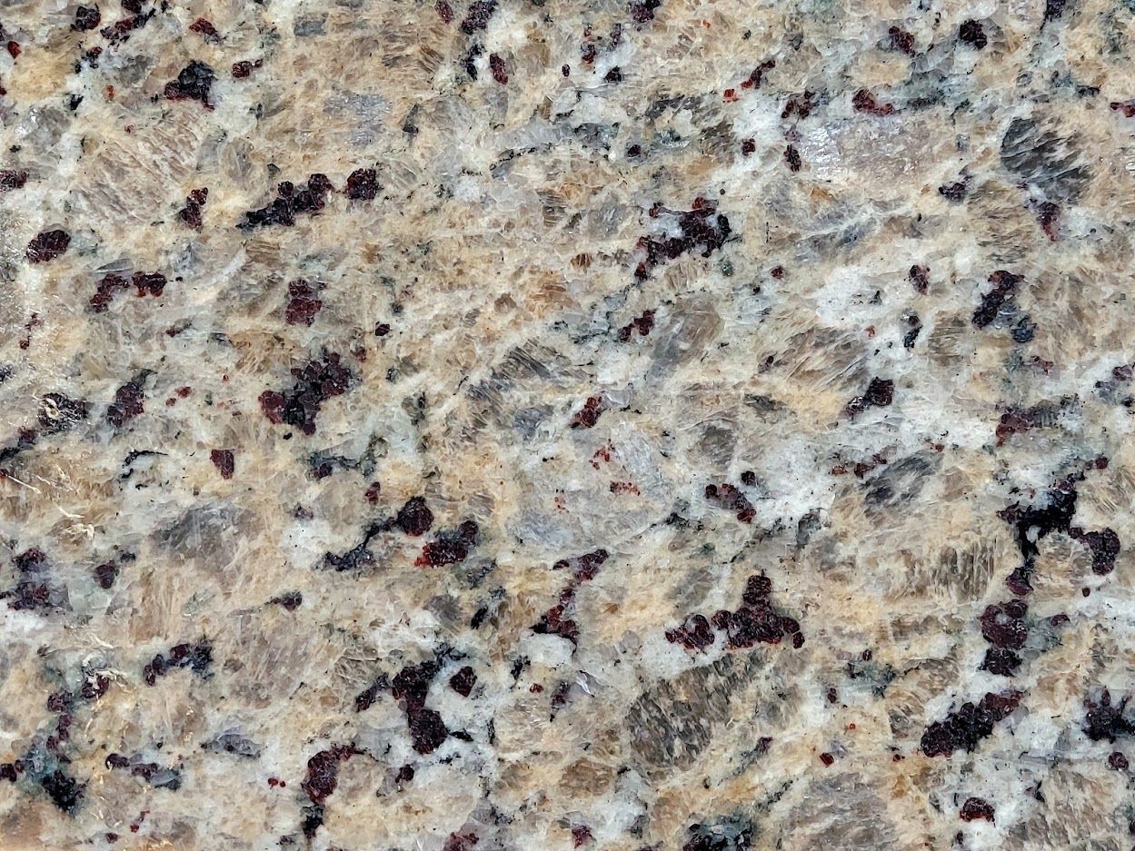 Close-up of granite countertop with tan, grey, and dark red speckles.
