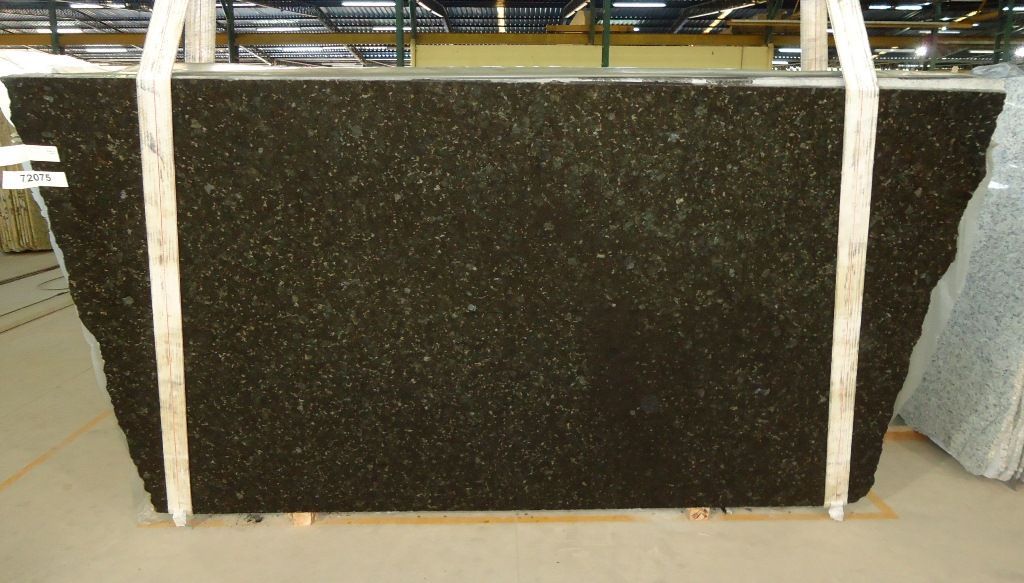 Dark granite slab, being transported with white straps in a warehouse setting.