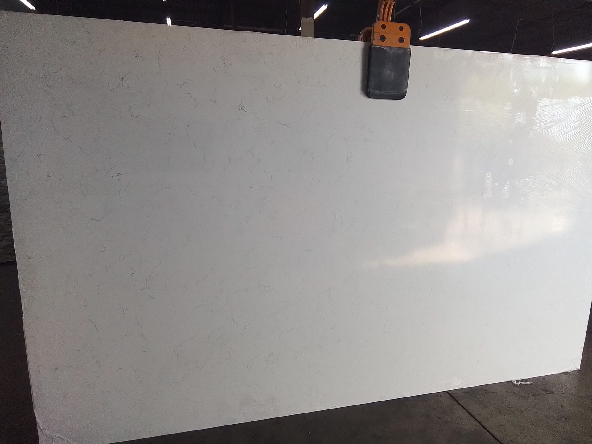 Large white slab of material being lifted by machinery in a warehouse.