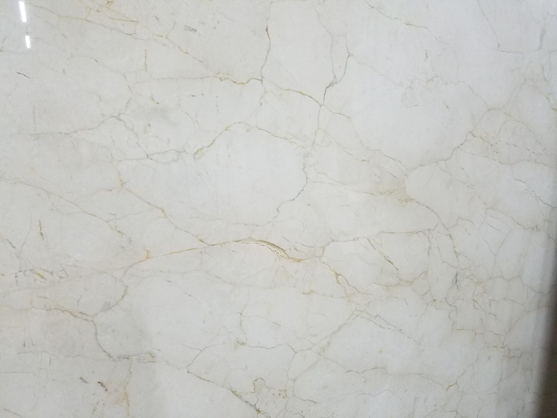 Cream-colored marble with brown veining and natural cracks.