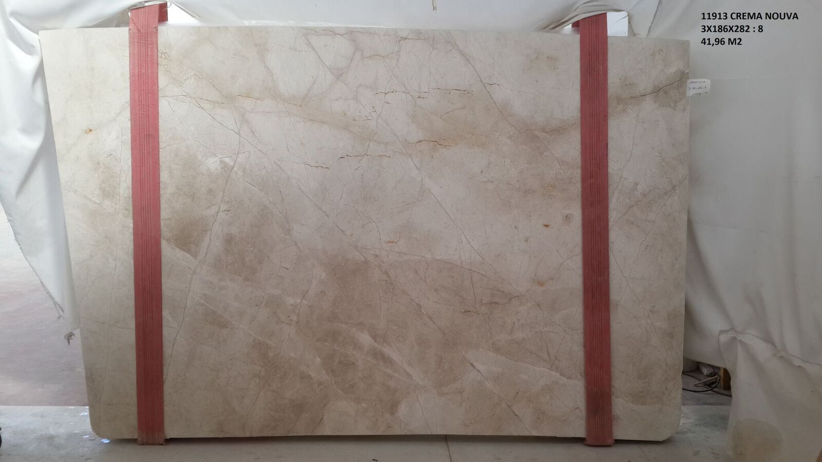 Cream-colored marble slab secured with two pink straps, ready for transport.