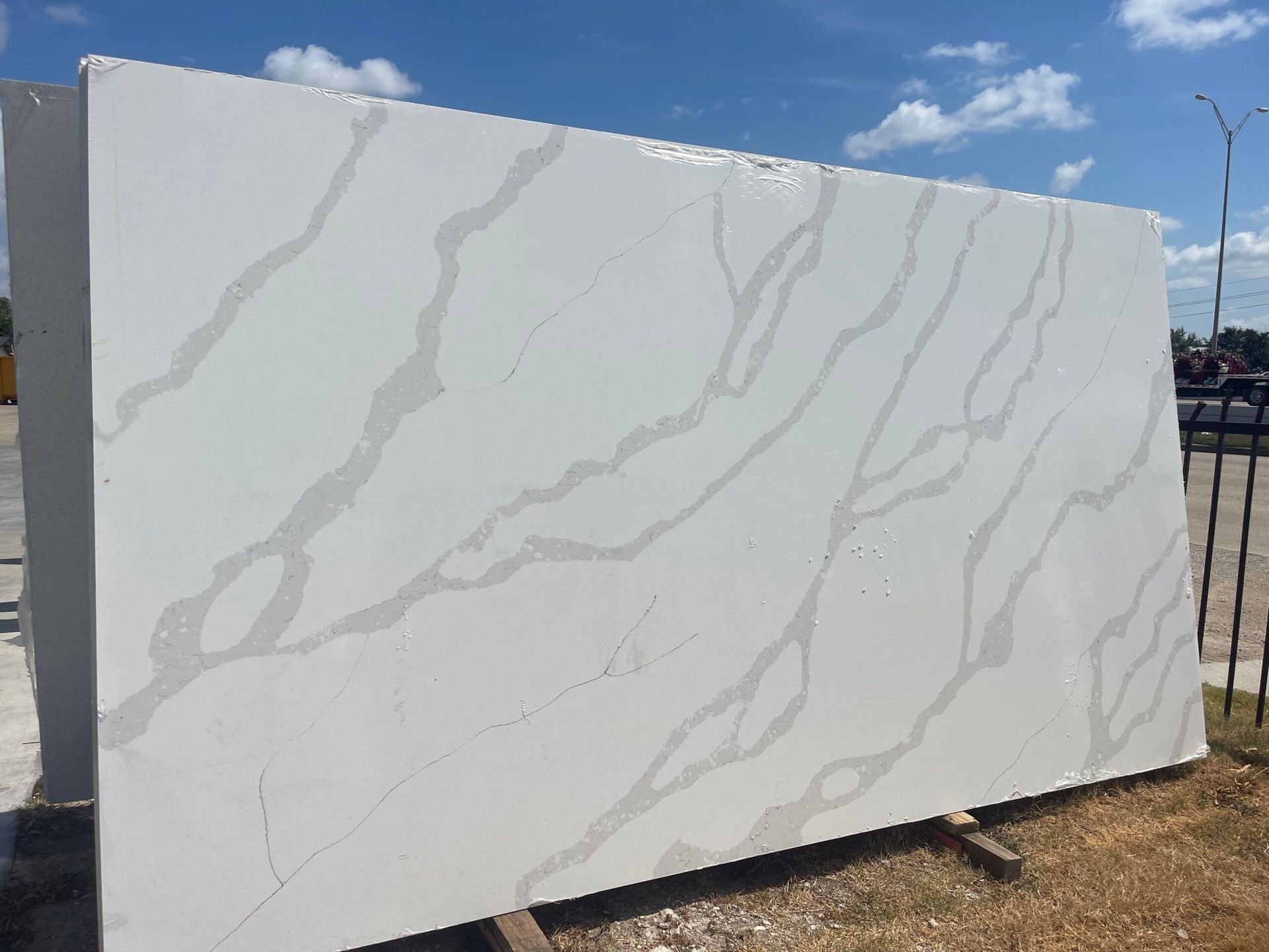 Large white quartz slab with gray veining, outdoors.
