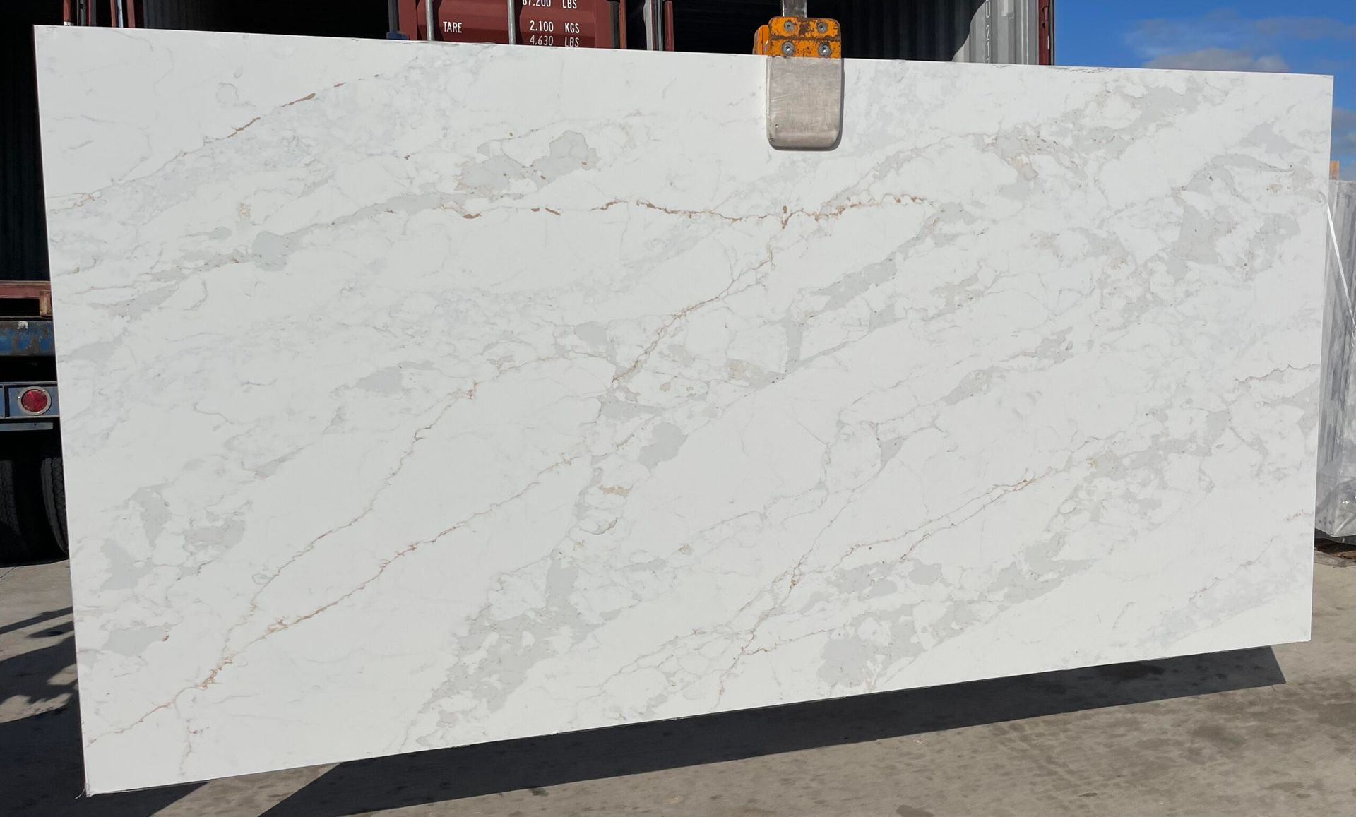 White stone slab with gray veining, being lifted outside.