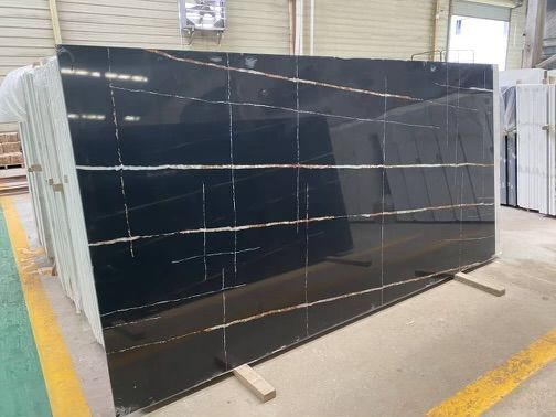 Black granite slab with gold veining, stacked in a warehouse.