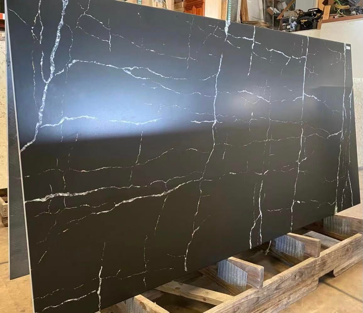 Black countertop slab with white veining, resting on wooden supports.
