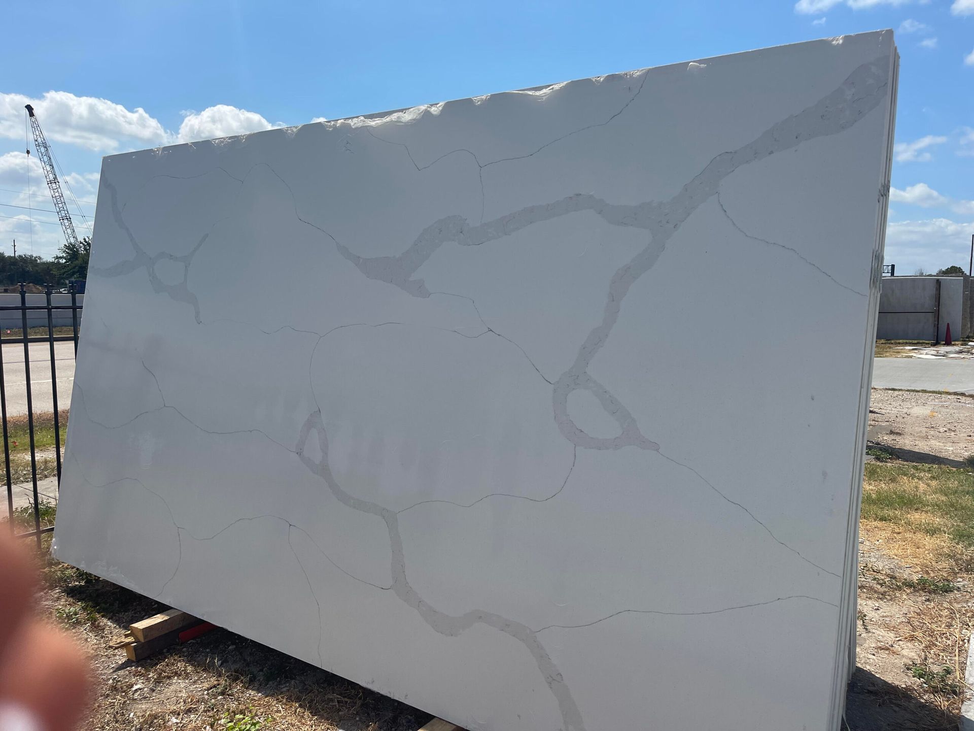 Large white stone slab with gray veining outdoors under a bright blue sky.