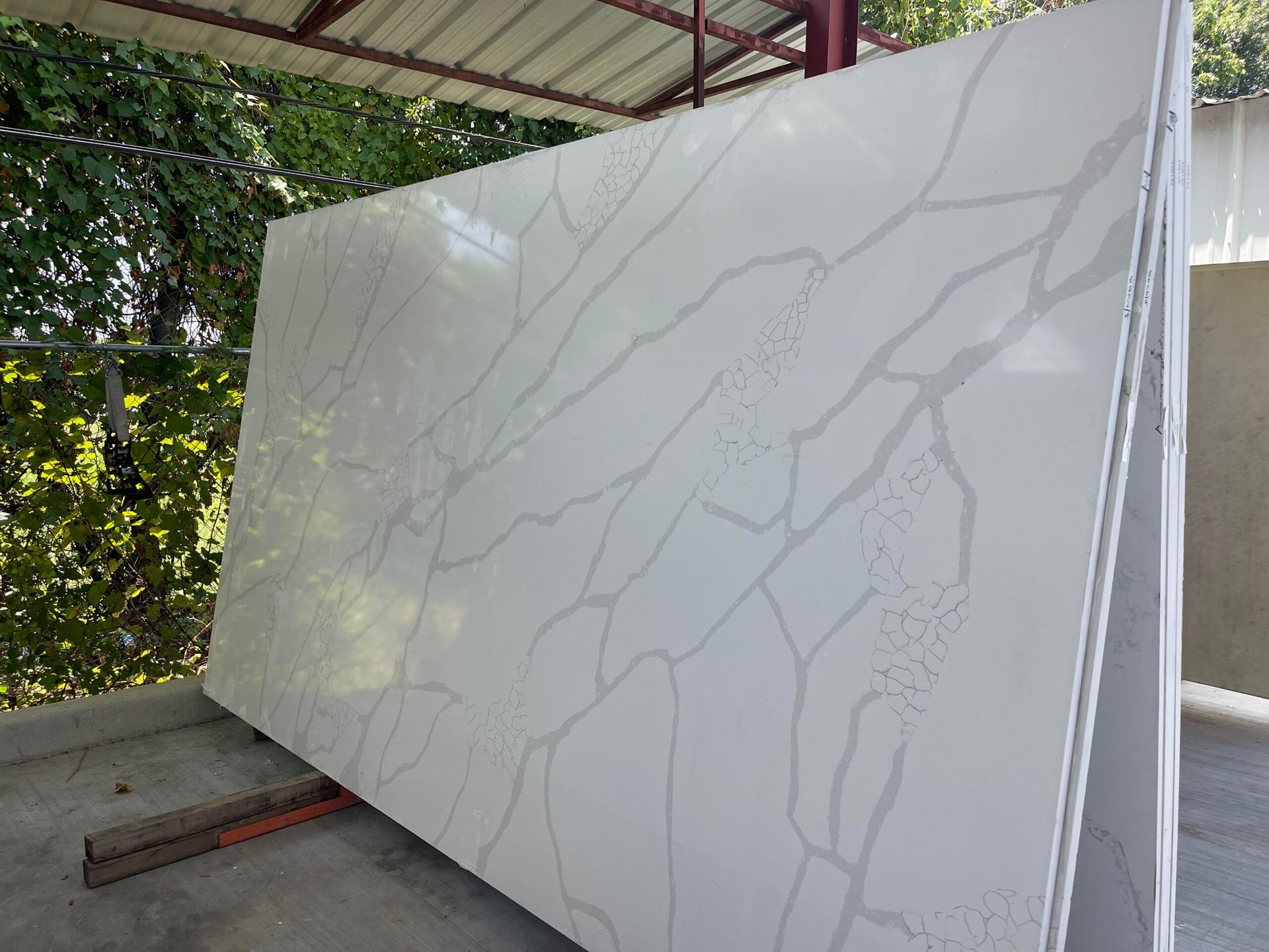 White quartz slab with gray veining, leaning outdoors.