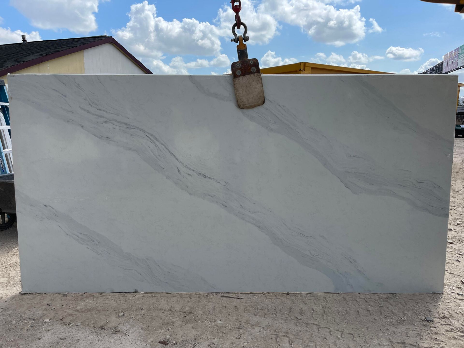 Large white stone slab with gray veining, hanging outdoors.