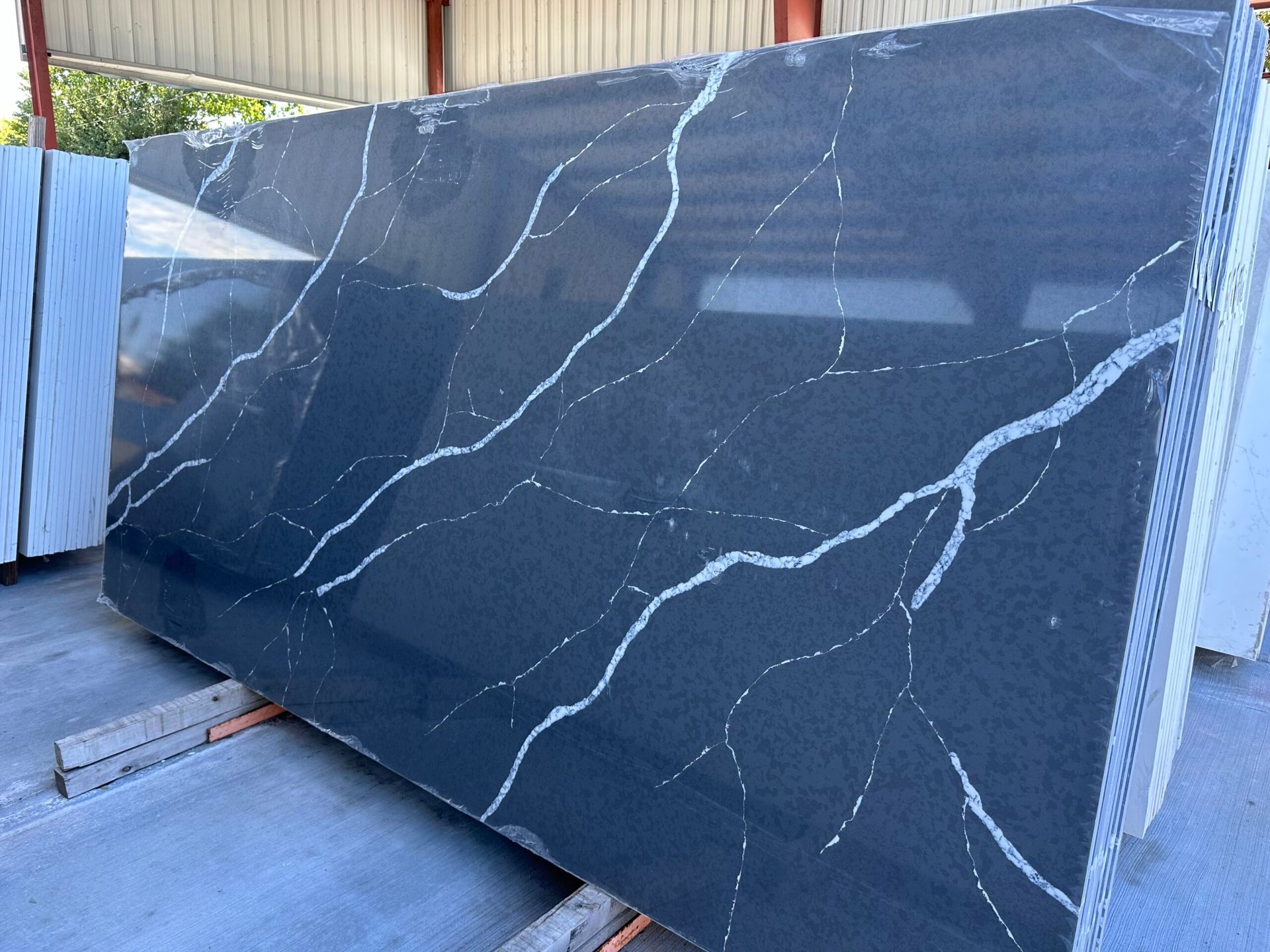 Dark gray countertop slab with white veining, indoors, stacked.
