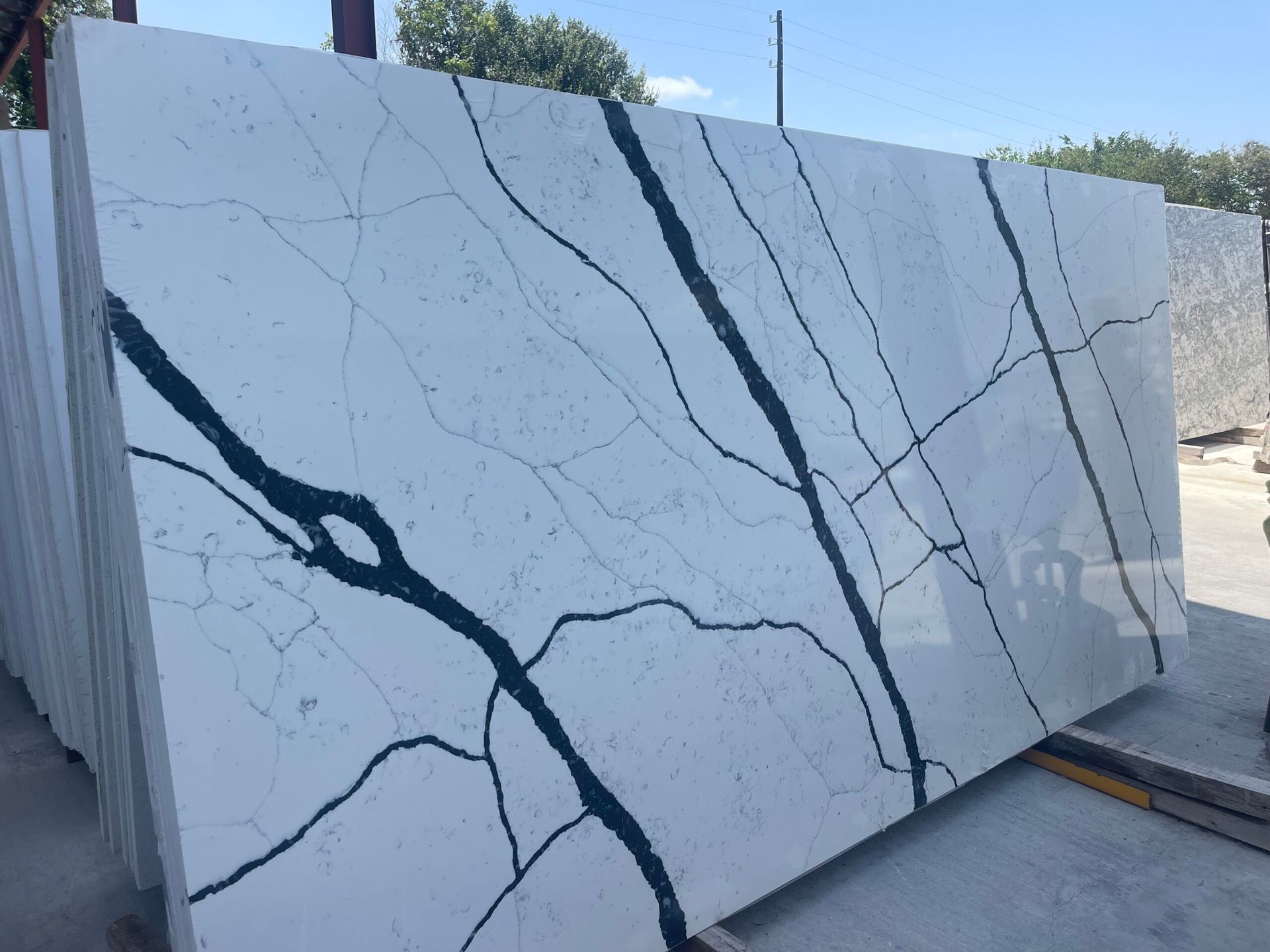 Large white stone slab with dark blue-grey veining, stacked outdoors.