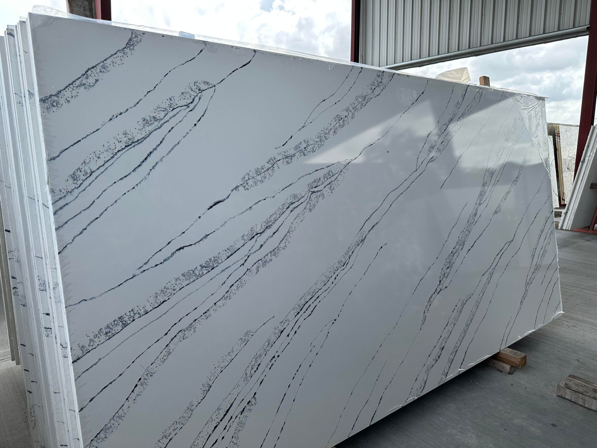 White quartz slabs with black veining, stacked indoors.