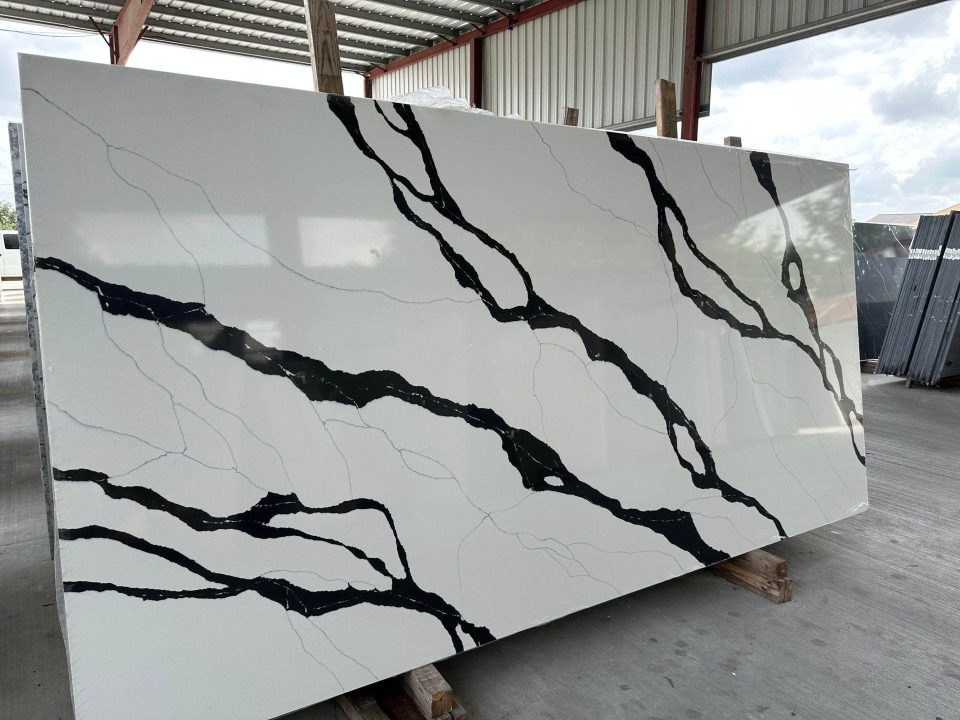 White quartz slab with bold black veining, displayed in a warehouse setting.