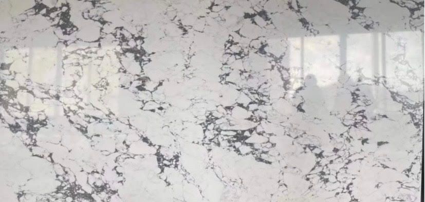 White and gray marbled countertop with a glossy finish; a reflection of a person is visible.