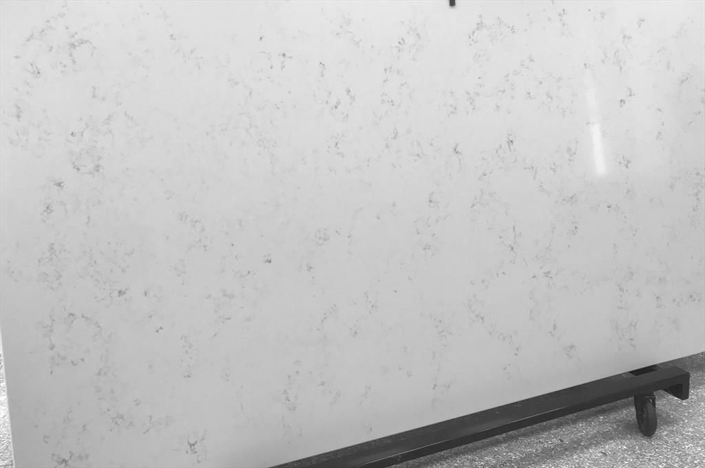 White countertop slab with gray veining, displayed on a black stand.