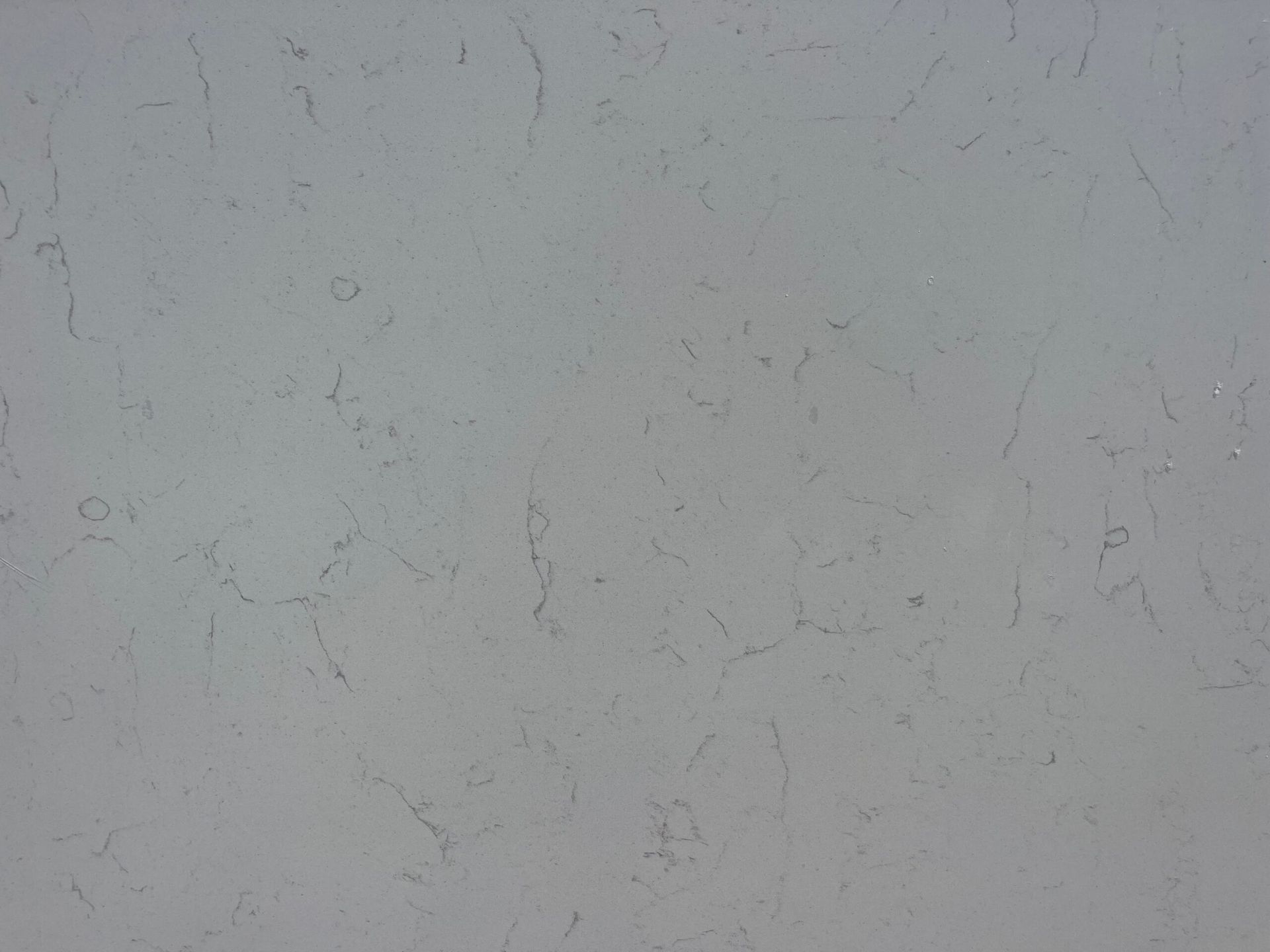 Gray, textured wall with subtle imperfections and small dark marks.