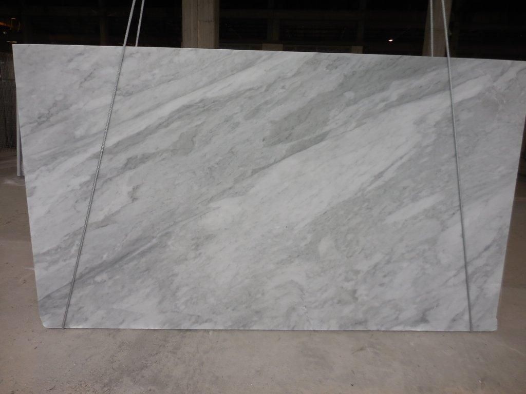 Large, rectangular slab of gray marble with flowing, light-gray veining, suspended by wires.