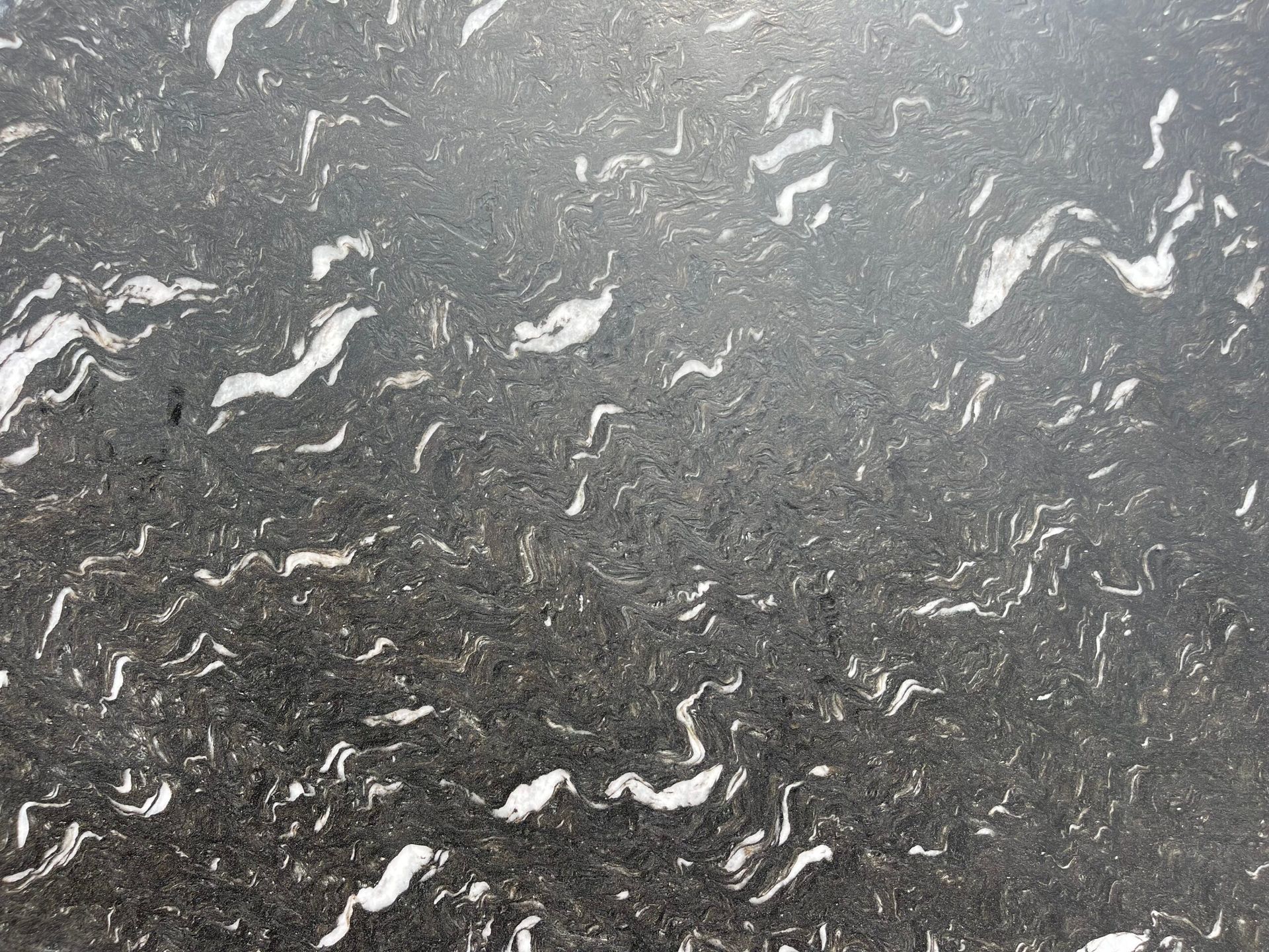 Dark gray granite with white wave-like patterns.