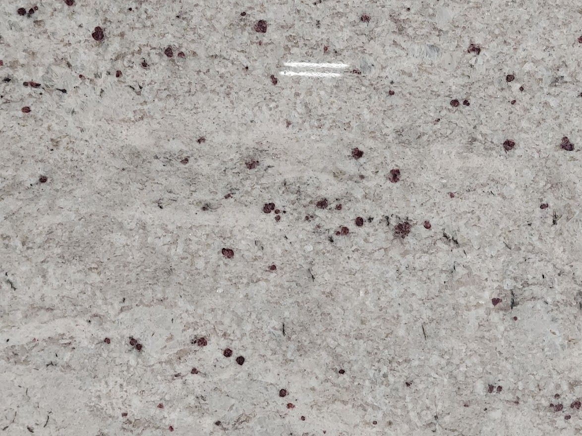 White granite with gray veining and scattered dark red speckles.