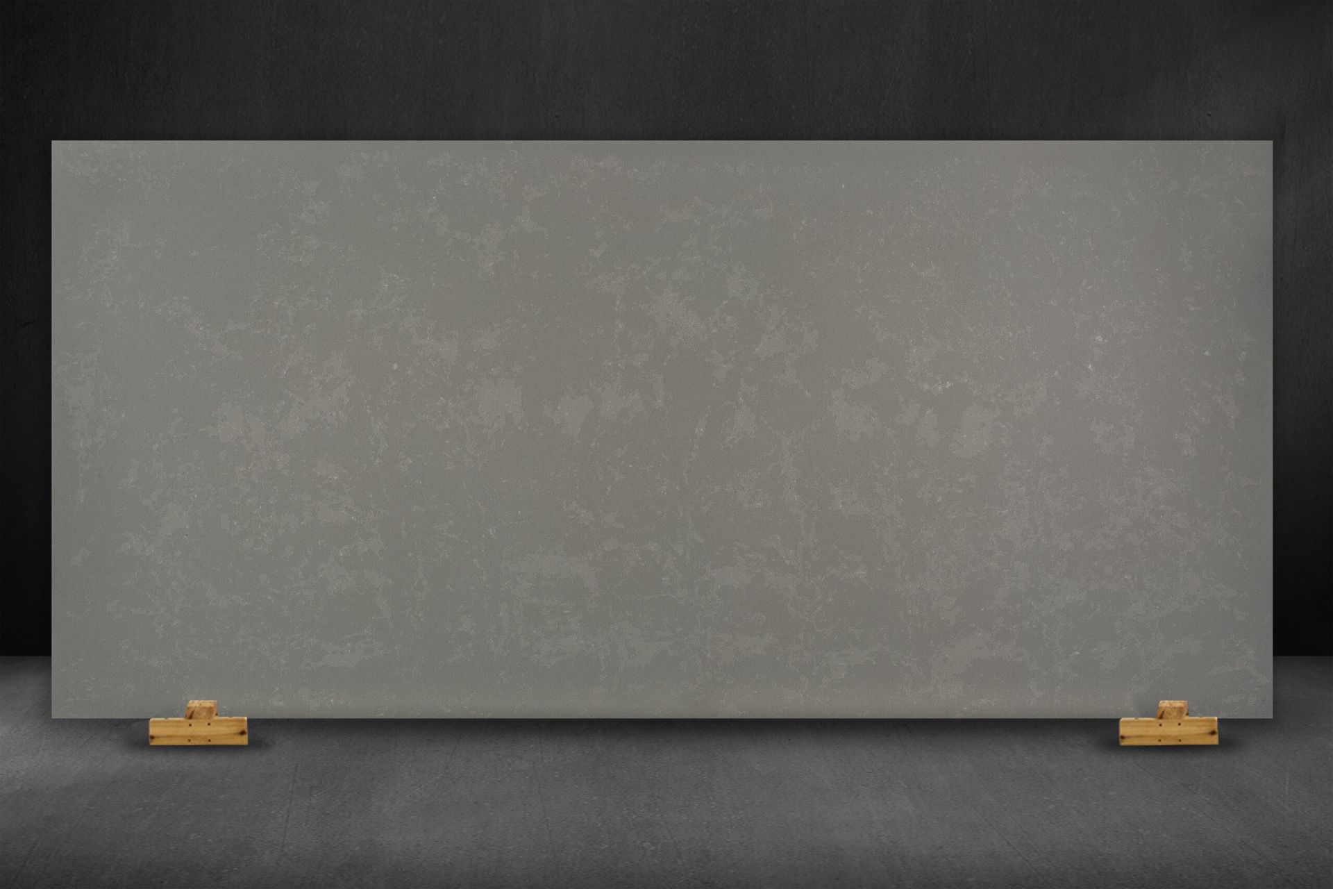 Gray quartz countertop slab, mounted on golden supports, against a dark gray background.