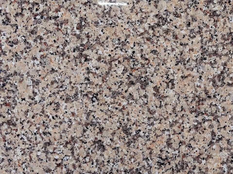 Tan granite surface with speckled black and gray mineral patterns.