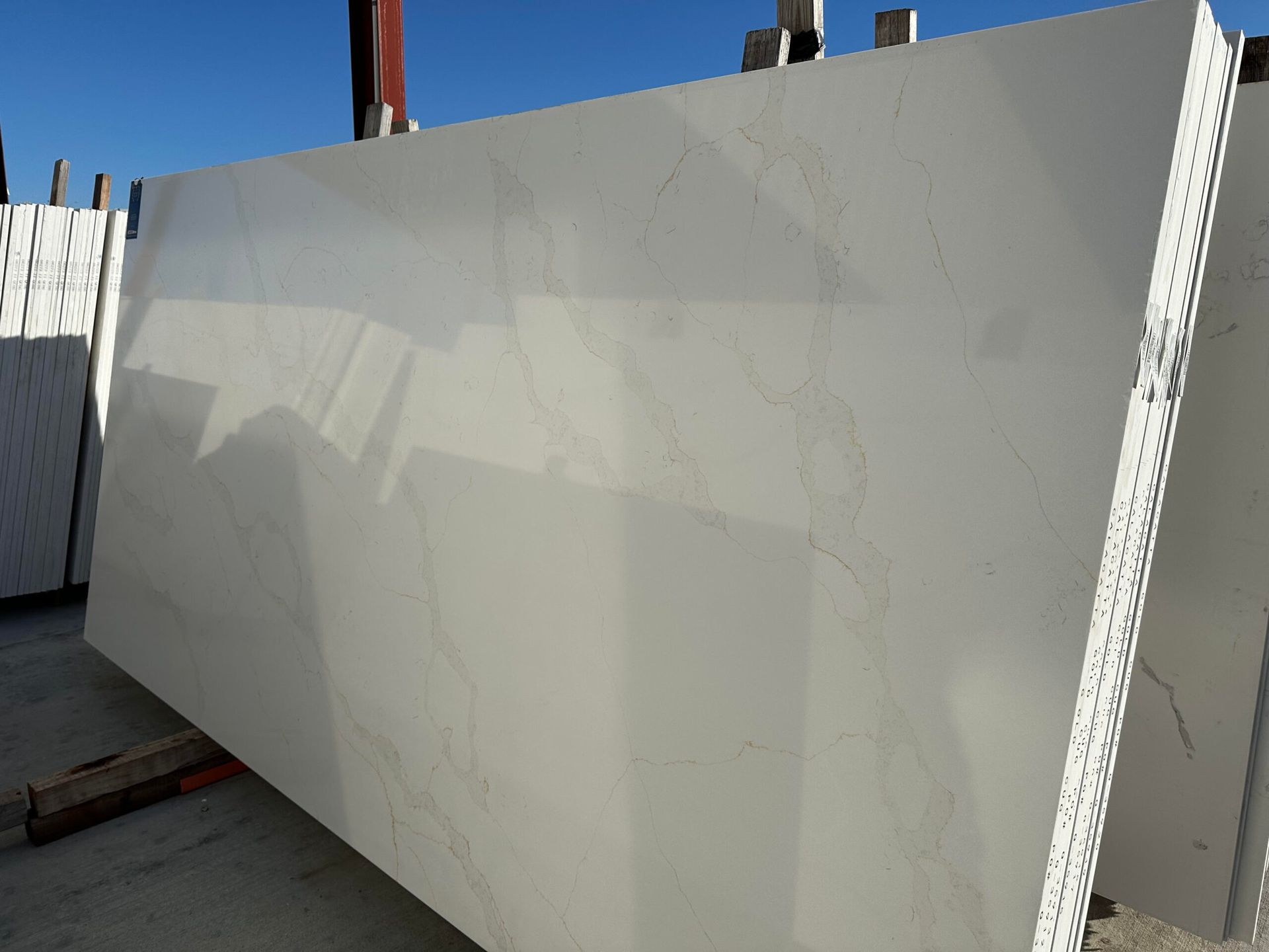 Large, white marble slab with subtle gray veining, resting outdoors.